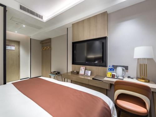 a hotel room with a bed and a flat screen tv at GreenTree Eastern Xuzhou High Speed Railway Station West Exit Station Hotel in Xuzhou