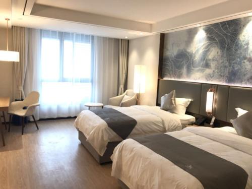 a hotel room with two beds and a window at GreenTree Eastern Xuzhou High Speed Railway Station West Exit Station Hotel in Xuzhou