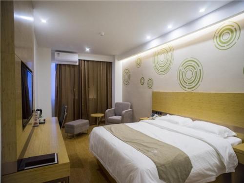 a hotel room with a large bed and a chair at GreenTree Inn Suzhou Kunshan Dongcheng Road International Exhibition Express Hotel in Penglang