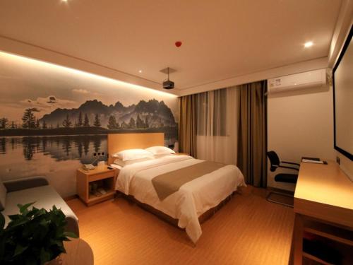 een hotelkamer met een bed en een schilderij aan de muur bij GreenTree Inn Zhengzhou Gongyi Xinxing Road Business Hotel in Zhengzhou