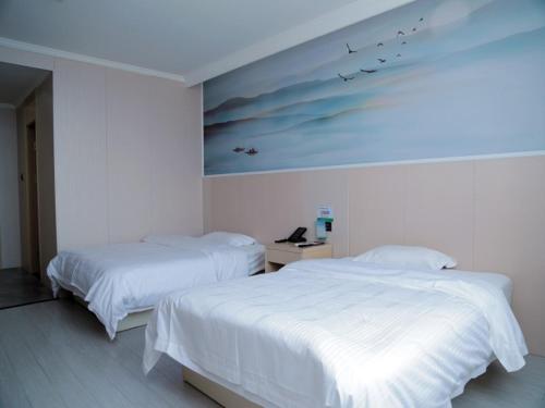 揚州市にあるGreenTree Inn Jiangsu Yangzhou West Passenger Station Baixiang Road Express Hotelの壁に絵画が飾られたベッドルーム1室(ベッド2台付)