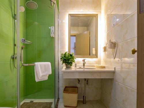 ein Bad mit einem Waschbecken und einer Dusche mit einem Spiegel in der Unterkunft GreenTree Inn Changzhou Zouqu Town Tai fu Times Square Zhenzhong Road Express Hotel in Changzhou