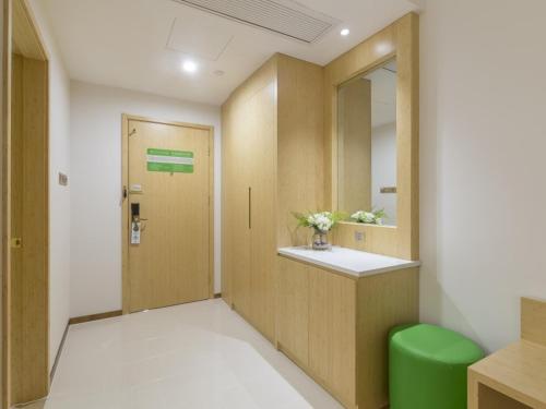 a room with a hallway with a door and a green stool at GreenTree Inn Xuzhou Ou Shasha Building Materials City Express Hotel in Xuzhou