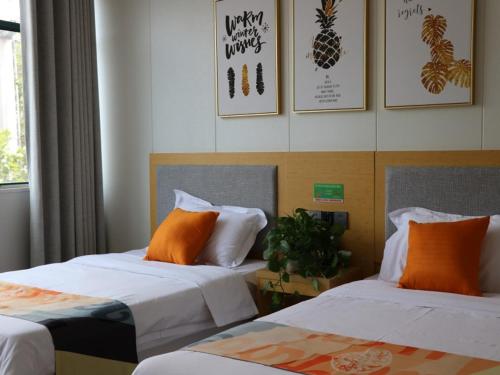 2 Betten mit orangefarbenen Kissen in einem Zimmer in der Unterkunft Shell Suzhou Chinese Medicine Hospital Hotel in Suzhou