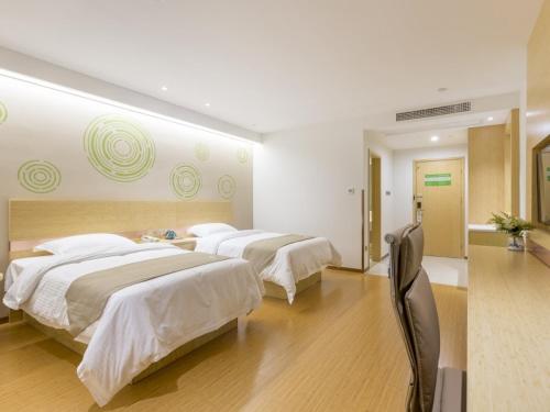 two beds in a large room with white walls at GreenTree Inn Xuzhou Ou Shasha Building Materials City Express Hotel in Xuzhou