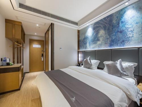 a bedroom with a large bed with a large painting on the wall at GreenTree Eastern Xuzhou High Speed Railway Station West Exit Station Hotel in Xuzhou