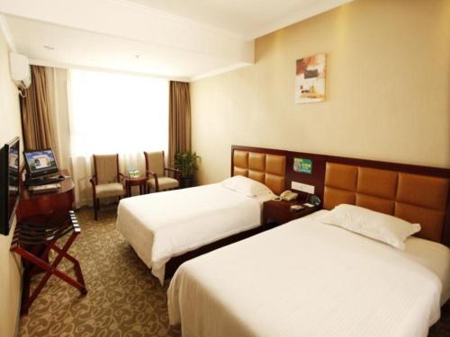 a hotel room with two beds and a television at GreenTree Inn Anhui Hefei Tianehu Wanda Square Express Hotel in Hefei