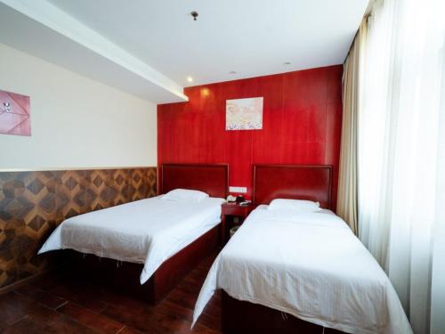 a bedroom with two beds and a red wall at GreenTree Inn Henan Zhengzhou Chengnan Road Bojue Business Hotel in Zhengzhou
