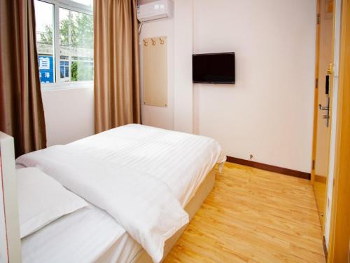 a bedroom with a white bed and a television at Shell Huai'an Fishing Hook Town Hotel in Huai'an
