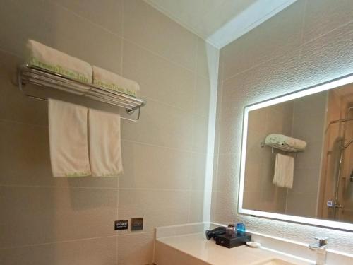 a bathroom with a sink and a large mirror at GreenTree Inn JiuJiang Railway Station Business Hotel in Jiujiang