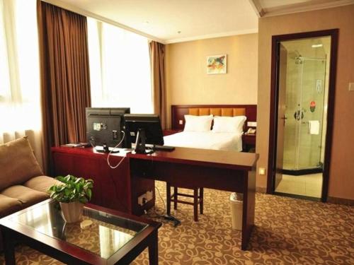 a hotel room with a desk and a bed at GreenTree Inn Anhui Hefei Tianehu Wanda Square Express Hotel in Hefei