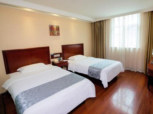 a hotel room with two beds and a window at GreenTree Inn Henan Zhengzhou West Changjang Road Business Hotel in Zhengzhou