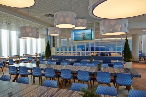 a rendering of a restaurant with blue chairs and tables at H2 Hotel München Messe in Munich