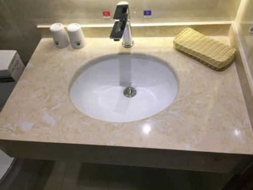 a bathroom sink with a white marble counter top at GreenTree Inn Beijing Tongzhou District Yujiawu Technology park Express Hotel in Tongzhou