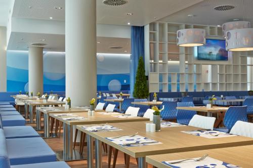 a restaurant with wooden tables and blue chairs at H2 Hotel München Messe in Munich