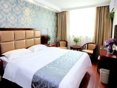 a bedroom with a large bed with a white bedspread at GreenTree Inn Henan Zhengzhou West Changjang Road Business Hotel in Zhengzhou