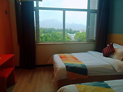a bedroom with two beds and a large window at Shell Tai'an Taishan District Xinhuacheng International Plaza Hotel in Tai'an