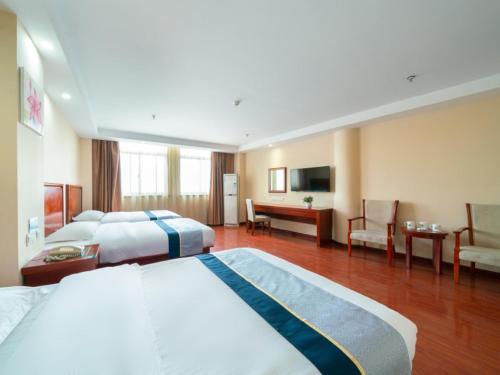 a hotel room with two beds and a desk at GreenTree Inn Jiangsu Suzhou Shengze Bus Station Business Hotel in Suzhou