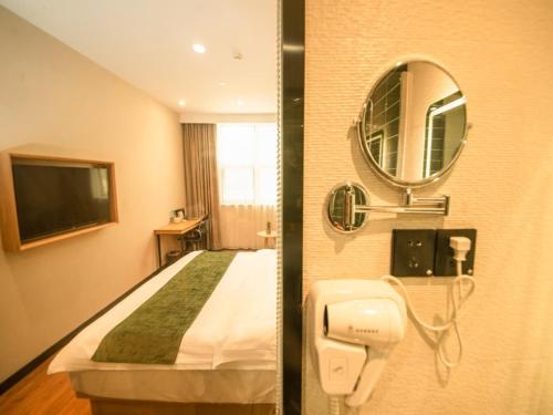 南京市にあるGreenTree Inn Nanjing Lukou Airportのベッドと鏡が備わるホテルルーム