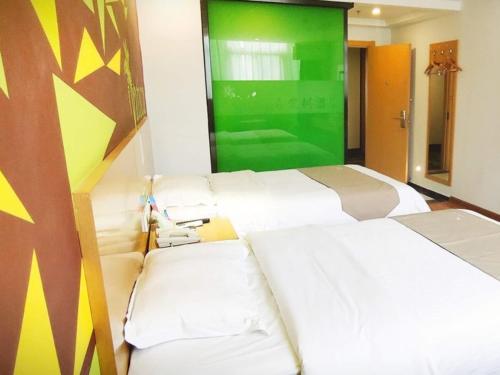 a room with three white beds and a green screen at Vatica Hefei Yaohai District Linquan Road Anhui Big Market Hotel in Hefei