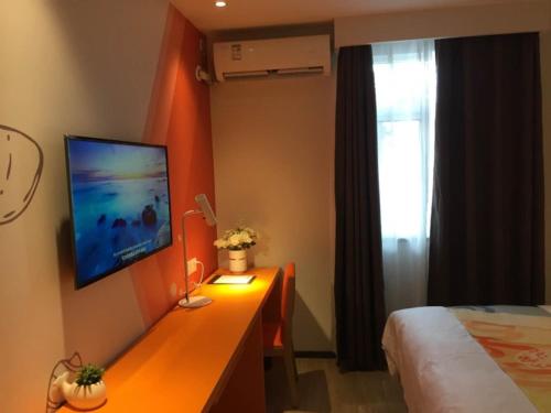 a bedroom with a desk with a television on the wall at Shell Tai'an Taishan District Xinhuacheng International Plaza Hotel in Tai'an