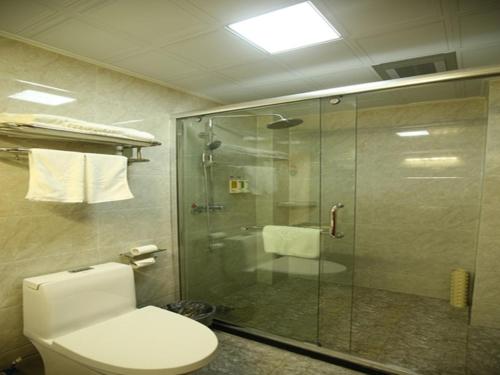 een badkamer met een toilet en een glazen douche bij GreenTree Alliance Shandong Linyi Mengyin Xincheng road Hotel in Mengyin