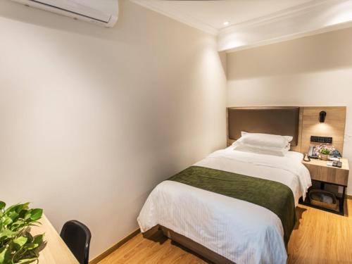 a bedroom with a large bed and a desk at GreenTree Inn Suzhou Humble Administrator's Garden Railway Station South Square in Suzhou
