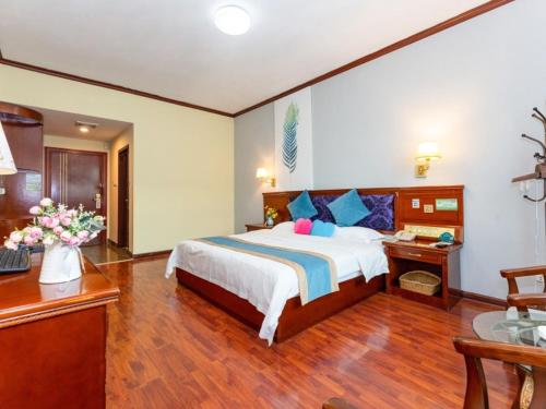 a bedroom with a large bed and a desk and a desk at GreenTree Inn Nanning Xiuxiang Branch in Nanning