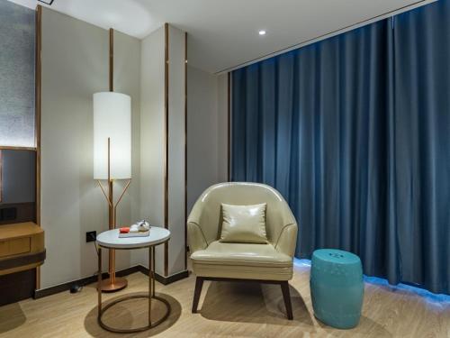 a living room with a chair and a table at GreenTree Eastern Xuzhou High Speed Railway Station Square Yindi Automobile Market Hotel in Xuzhou