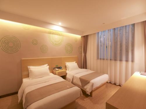 a hotel room with two beds and a window at GreenTree Inn Wuxi Rongchuang cultural Tourism City Nanquan Town Business Hotel in Wuxi