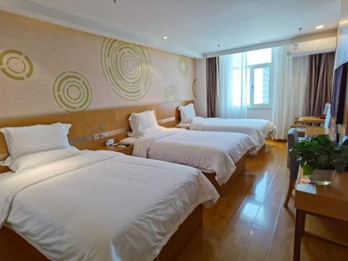 um quarto de hotel com três camas com lençóis brancos em GreenTree Xining Chengzhong Area Dongguan Street Street Hotel em Xining