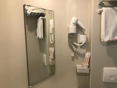 a mirror in a bathroom with a phone at Shell Jinan Gaoxin District Shunhua Road Qilu Software Park Hotel in Jinan