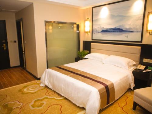 a bedroom with a large bed and a painting on the wall at GreenTree Alliance Texas Ningjin County Zhengyang Road Debai Plaza Hotel in Dezhou