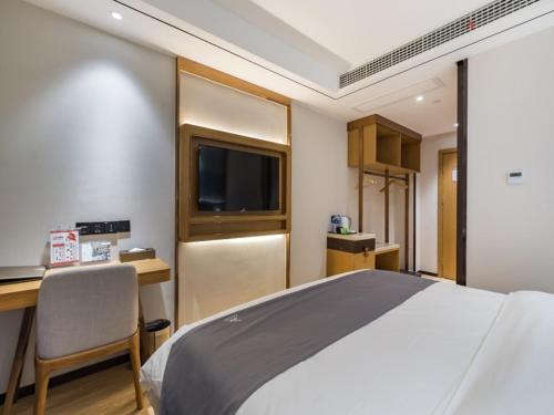 a bedroom with a bed and a desk and a television at GreenTree Eastern Xuzhou High Speed Railway Station West Exit Station Hotel in Xuzhou
