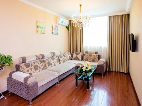 a living room with a couch and a table at GreenTree Inn Henan Zhengzhou West Changjang Road Business Hotel in Zhengzhou