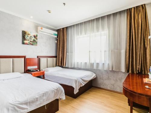a bedroom with two beds and a desk and a window at GreenTree Inn Shanghai Huinan Jinghai Road Express Hotel in Nanhui