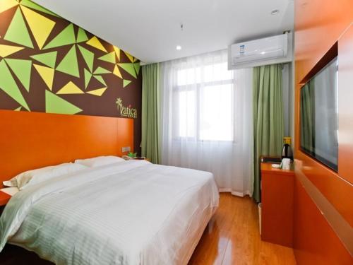 a bedroom with a large bed and a flat screen tv at Vatica Hefei Yaohai District Wangang Road Metro Station Hotel in Hefei