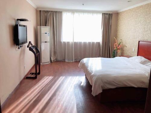 a bedroom with a bed and a flat screen tv at GreenTree Inn Jiangsu Suzhou Chang Shu Aotelaisi Business Hotel in Changshu