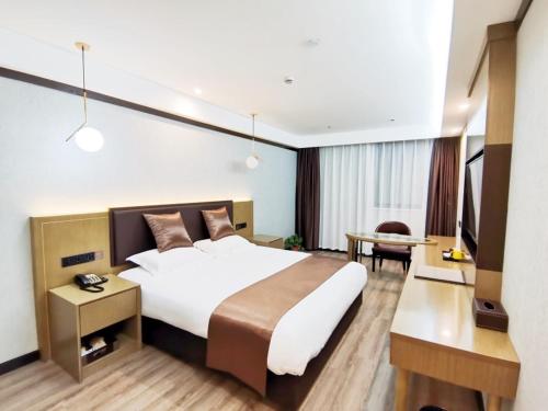 a hotel room with a large bed and a desk at Gya Taizhou Jingjiang City South Century Plaza Hotel in Jingjiang