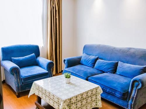 a living room with two blue couches and a table at GreenTree Inn Anhui Xuancheng South Zhuangyuan Road Express Hotel in Xuanzhou
