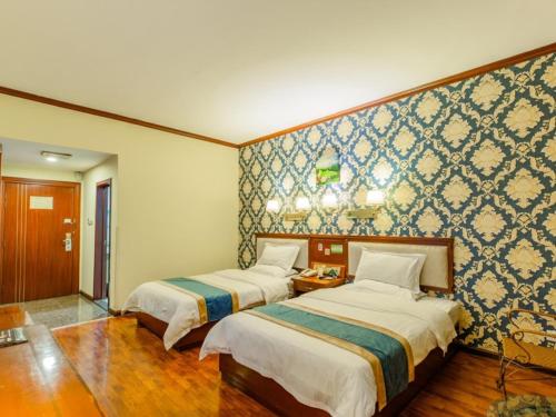 a bedroom with two beds and a wall with blue tiles at GreenTree Inn Nanning Xiuxiang Branch in Nanning