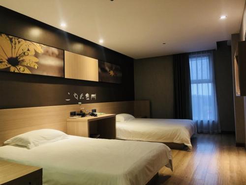 een hotelkamer met 2 bedden en een spiegel bij Gemeng Langfang Wen'an County Economic Development Zone Fengli Road Hotel in Wen'an