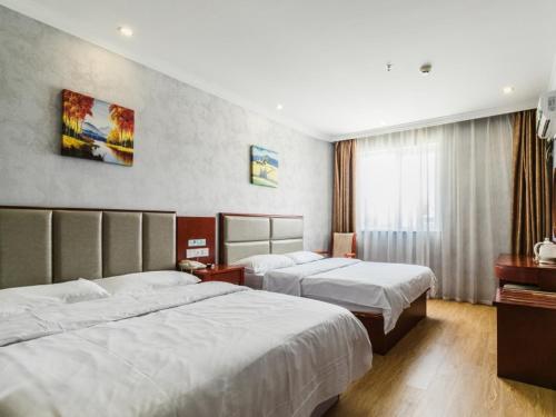 a hotel room with two beds and a window at GreenTree Inn Shanghai Huinan Jinghai Road Express Hotel in Nanhui