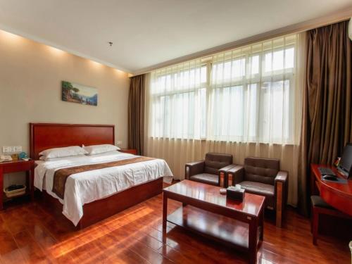 a hotel room with a bed and a chair and a table at GreenTree Inn HeNan XinXiang LaoDong S) Street ZangYing Bridge Business Hotel in Xinxiang
