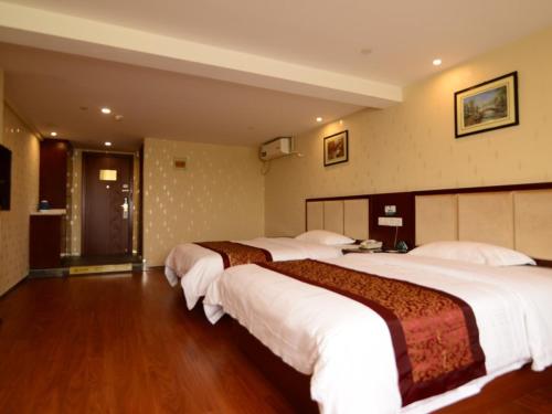 a hotel room with three beds in a room at GreenTree Inn JiangSu Suzhou Kunshan Huaqiao in Kunshan
