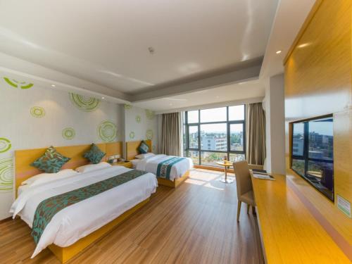 a hotel room with two beds and a large window at GreenTree Inn Qionghai Boao Railway Station Business Hotel in Qionghai