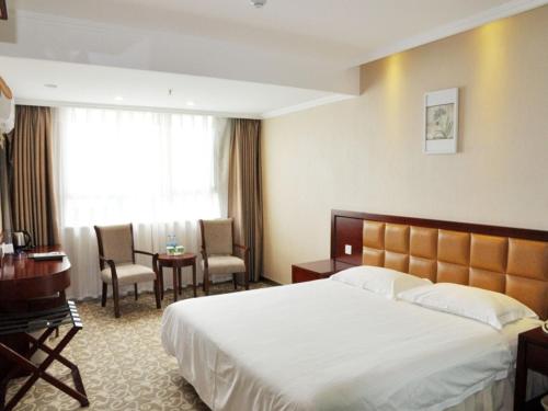 a hotel room with a large bed and a desk at GreenTree Inn Anhui Hefei Tianehu Wanda Square Express Hotel in Hefei