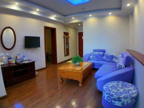 a living room with a blue couch and a table at GreenTree Inn Henan Kaifeng Gulou Square Express hotel in Kaifeng