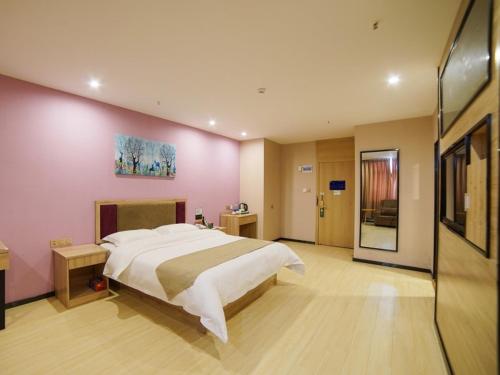 a bedroom with a large bed and a pink wall at GreenTree Alliance Kunming Beijing Road Linyuqiao Subway Station Hotel in Kunming