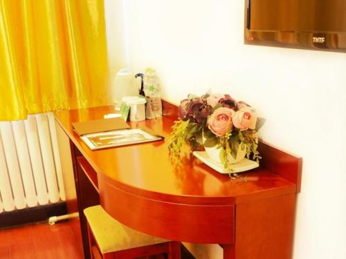 a wooden desk with a bouquet of flowers on it at GreenTree Inn Beijing Chaoyang Shilihe Antique City Express Hotel in Beijing